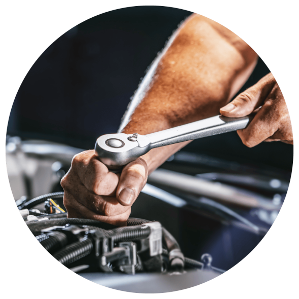 An image of a mechanic's hands using a ratchet wrench to make an adjustment on a car engine.