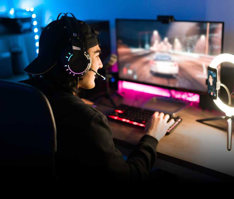 A male wearing a headset is playing a video game while entertaining his audience on a streaming platform.